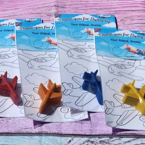Puede incluir: Cuatro p&aacute;ginas para colorear con un avi&oacute;n en un cielo azul y nubes. Cada p&aacute;gina incluye un peque&ntilde;o cray&oacute;n en forma de avi&oacute;n de color rojo, naranja, azul y amarillo.