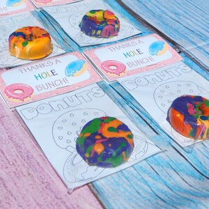 May include: A set of five donut-shaped crayons, each packaged in a clear plastic bag with a printable card. The cards feature a donut outline and the text "Thanks a Hole Bunch!" and "Donuts".