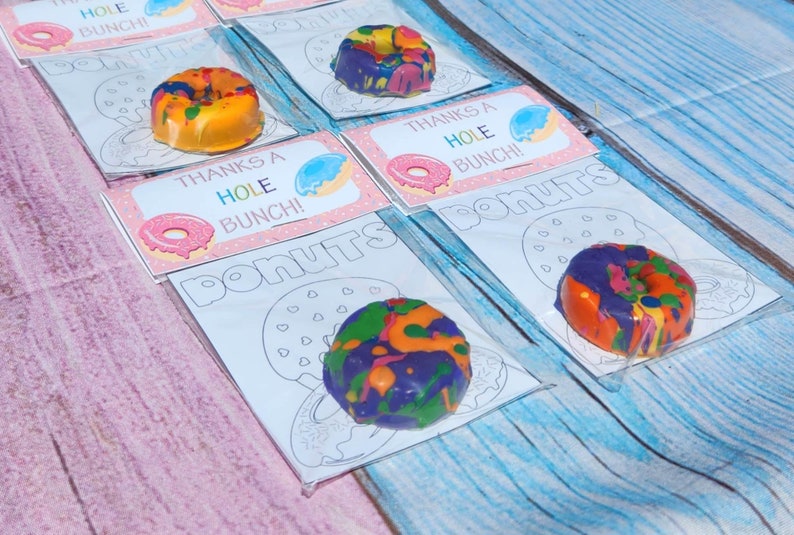 May include: A set of five donut-shaped crayons, each packaged in a clear plastic bag with a printable card. The cards feature a donut outline and the text "Thanks a Hole Bunch!" and "Donuts".