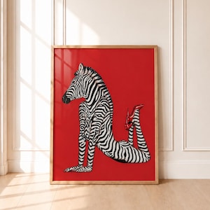 May include: A framed rectangular wall art print featuring a surreal illustration of a zebra with a human-like torso and limbs, posed on its hands and knees against a solid red background. The figure wears a single bright red high-heeled shoe.