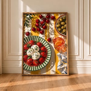 Könnte beinhalten: Ein gerahmter, rechteckiger Wandkunstdruck mit einem lebendigen Stillleben. Die Komposition umfasst einen Teller mit Mozzarella und Tomaten, eine Schale mit grünen Oliven, ein Glas mit einem orangefarbenen Cocktail und verstreute rote Kirschen.