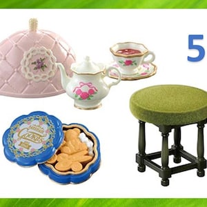Könnte beinhalten: Miniatur-Teeservice mit rosa Teewärmer, weißer Teekanne mit rosa Rosen, Tasse und Untertasse, grünem Hocker und blauer Keksdose mit bärenförmigen Keksen. Die Zahl 5 ist im Hintergrund zu sehen.
