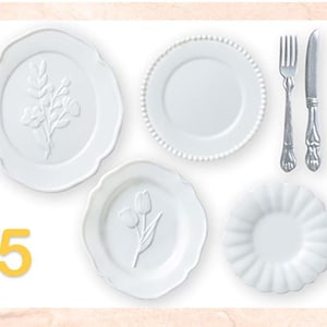 May include: A collection of white ceramic plates with embossed floral designs, a beaded edge, and a scalloped edge. Silverware, including a fork and knife, is also present. The number "5" is in the lower left corner.