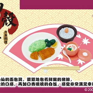 以下が含まれることがあります： トンカツ、ご飯、小鉢を配したミニチュアの日本食セット。ピンクの扇形の皿に盛り付けられ、日本語のテキストと装飾的な背景が特徴です。