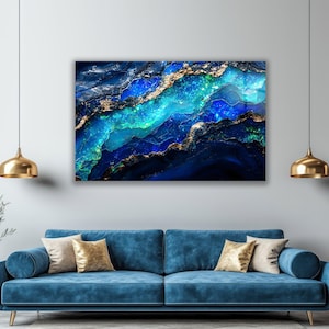 May include: Abstract art print featuring a vibrant display of blues, teals, and gold. The artwork resembles a geological formation or a celestial landscape, with flowing patterns and shimmering details. The piece is mounted on a wall above a blue sofa.