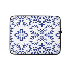 Può includere: Una custodia bianca per laptop con un motivo floreale blu ripetuto. Il design presenta fiori e viti stilizzati su sfondo bianco. La custodia ha un bordo nero e una chiusura a cerniera.