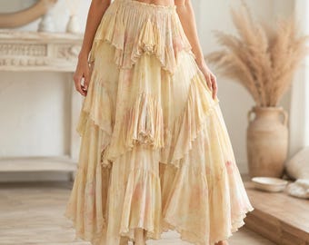 May include: A long, tiered skirt in a soft yellow and pink colour palette. The skirt has a flowing design with multiple ruffled layers, creating a bohemian style. The fabric looks lightweight and airy, ideal for warmer weather. The skirt's design suggests a casual, yet elegant style.