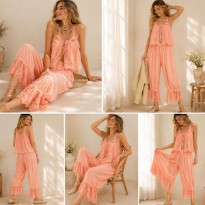 May include: A peach-coloured pajama set. The camisole top has lace trim and drawstring detail, paired with wide-leg pants with a ruffled lace hem. The set is made of a lightweight fabric. The outfit is suitable for relaxing at home.