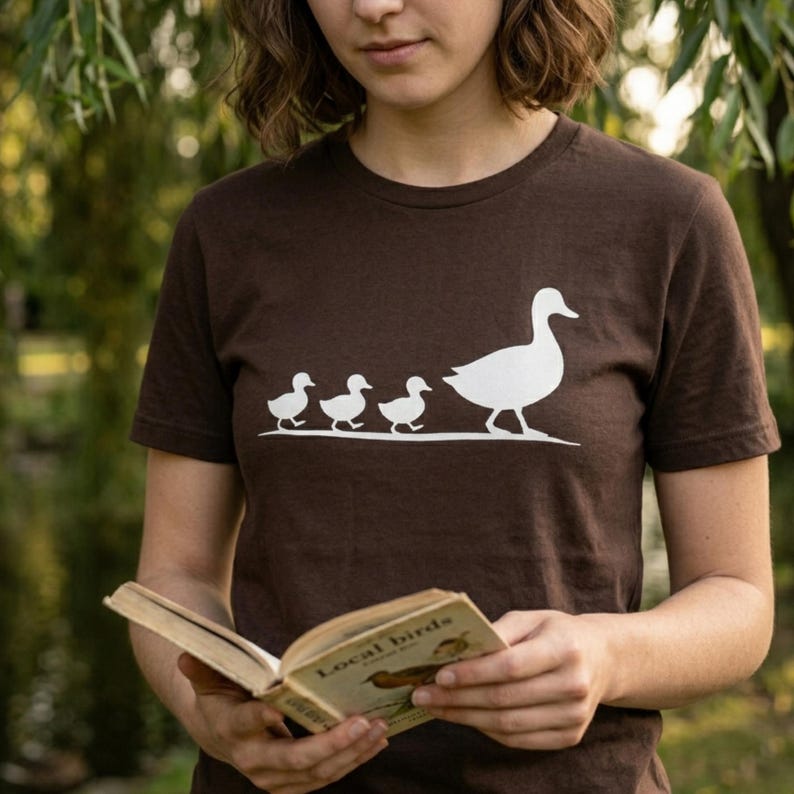 Minimalist mama duck graphic t-shirt featuring duck family silhouette design on soft burgundy cotton tee.