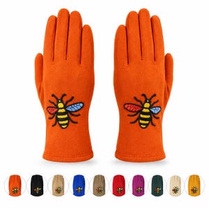 May include: A pair of orange gloves featuring an embroidered bee design on the back of each hand. The bee has a yellow and black striped body with one red wing and one blue wing. Below the main gloves are ten small circular colour swatches.