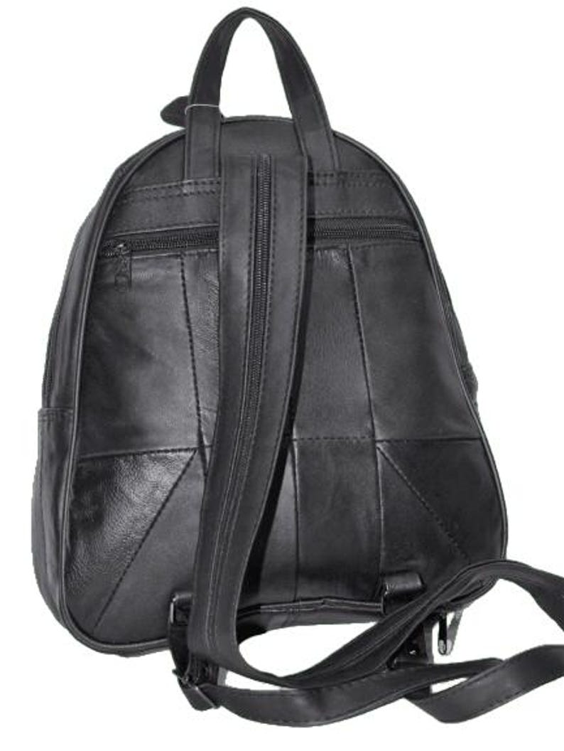 May include: A black leather backpack featuring a vertical zippered compartment on the back panel, a top carry handle, and adjustable shoulder straps. The exterior is constructed from multiple stitched leather panels with a smooth finish.
