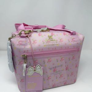 Pode incluir: Bolsa t&eacute;rmica rosa com estampa floral, al&ccedil;a superior e la&ccedil;o decorativo. A bolsa tem fecho de z&iacute;per e uma etiqueta com o texto "FOR ALL DAY MILLENNIAL COOLER". A bolsa tem o texto "STANLEY LOVESHACKFANCY".