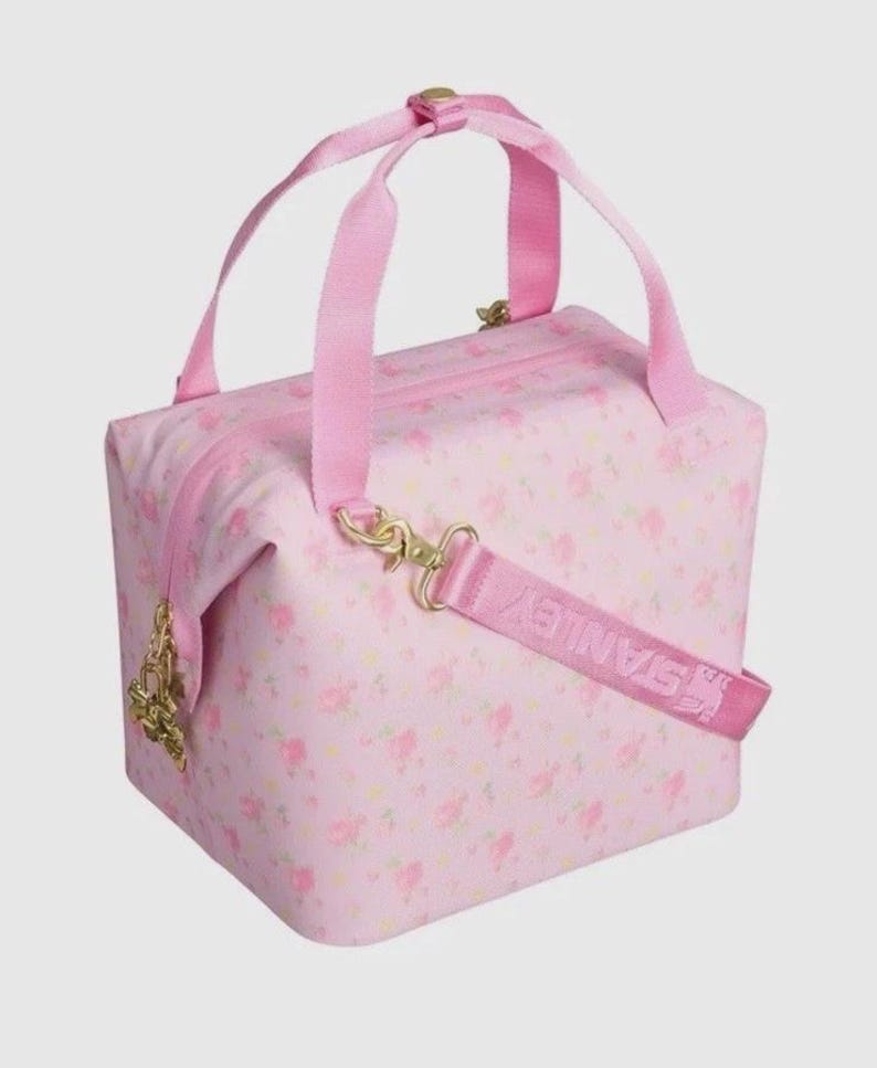 Pode incluir: Mala de viagem rosa com padr&atilde;o floral, com uma al&ccedil;a superior e uma al&ccedil;a de ombro remov&iacute;vel. A mala tem um fecho de correr e ferragens douradas. A palavra "STANLEY" est&aacute; impressa na al&ccedil;a de ombro.