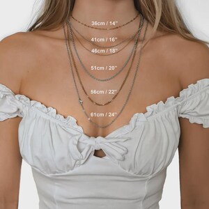 May include: A collection of layered necklaces in gold and silver. The image shows the necklaces with their lengths indicated in both centimetres and inches: 36cm/14", 41cm/16", 46cm/18", 51cm/20", 56cm/22", and 61cm/24".