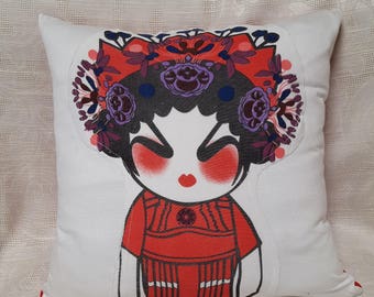 Könnte beinhalten: Ein weißes Kissen mit einer roten, violetten und schwarzen Comicfigur, die ein rotes Kleid und eine Blumenkrone trägt. Die Figur hat schwarze Haare und rote Wangen.