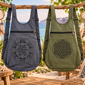May include: Two canvas backpacks, one charcoal gray and one olive green, each featuring adjustable shoulder straps and a horizontal zippered pocket. The gray bag displays a complex geometric mandala print, while the green bag features a flower of life pattern.