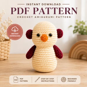 May include: A crochet amigurumi doll featuring a cream-colored body and head, dark maroon ears and arms, and a bright orange nose. The doll has large black eyes with gold rims. Text on the image reads PDF PATTERN CROCHET AMIGURUMI PATTERN.