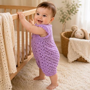 May include: A light purple crochet romper featuring a delicate openwork pattern, scalloped cap sleeves, and small wooden buttons on the bodice. The garment is crafted with a textured stitch design, providing a soft and lightweight appearance for infants.