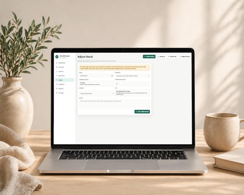 Pode incluir: Um laptop exibindo a interface "Ajustar Estoque" do aplicativo StockSimple. A tela mostra detalhes do invent&aacute;rio. Uma caneca bege e um livro est&atilde;o &agrave; direita. Um vaso com vegeta&ccedil;&atilde;o e um pano dobrado est&atilde;o &agrave; esquerda.