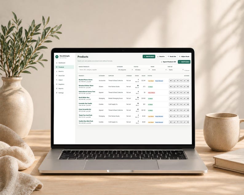 Pode incluir: Um laptop exibindo um painel de controle de gerenciamento de estoque de produtos. A tela mostra detalhes do produto, categorias e n&iacute;veis de estoque. Uma caneca bege, um livro e um vaso com vegeta&ccedil;&atilde;o est&atilde;o na mesa de madeira.