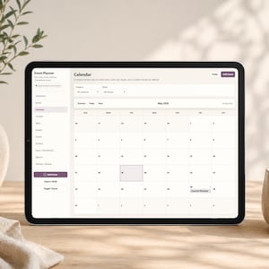 May include: A digital tablet displays an event planner calendar interface. The screen shows a monthly calendar view for May 2026, with options for categories and filters. The tablet is on a wooden surface, next to a vase and a ceramic cup.