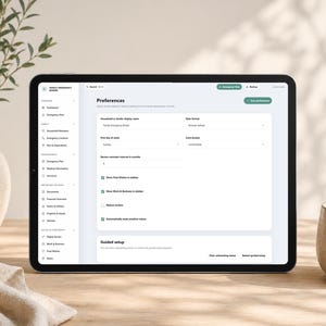 May include: A tablet screen displaying a digital interface titled Family Emergency Binder. The screen shows a Preferences menu with settings for display name, date format, and various checkboxes for data visibility and guided setup options.