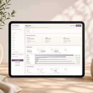 May include: A black tablet displaying an event planner app interface with financial reports. The screen shows data visualizations, budget summaries, and event details. A vase with greenery and a ceramic cup are in the background.