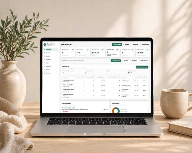Pode incluir: Um laptop exibindo uma interface de painel com dados de invent&aacute;rio. A tela mostra detalhes do produto, n&iacute;veis de estoque e m&eacute;tricas financeiras. Um vaso com vegeta&ccedil;&atilde;o, uma caneca e um livro est&atilde;o na mesa de madeira.