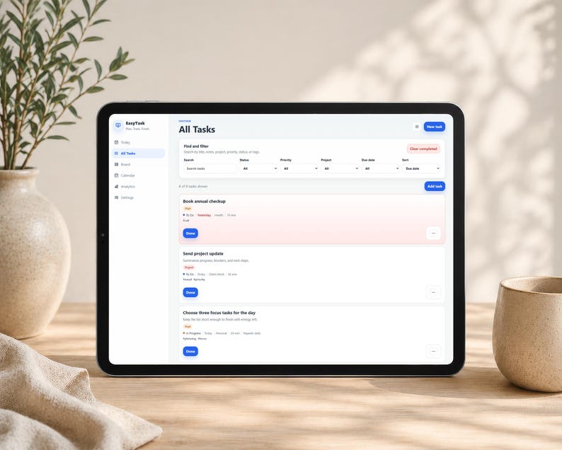 Może przedstawiać: Czarny tablet wyświetlający interfejs aplikacji "EasyTask", z ekranem zarządzania zadaniami zatytułowanym "All Tasks". Ekran zawiera listy zadań, filtry wyszukiwania i niebieski przycisk "Add task". Beżowy wazon i ceramiczny kubek znajdują się w tle.