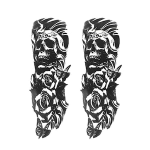 Può includere: Due tatuaggi temporanei neri con un design a teschio con rose e farfalle. I tatuaggi presentano ombreggiature e linee dettagliate, creando un'estetica gotica e artistica. Adatto per braccia o gambe.