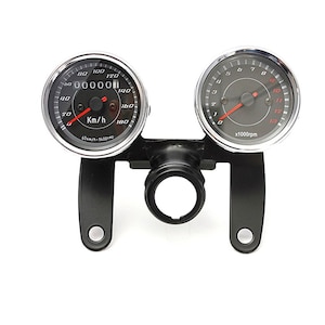 May include: A motorcycle speedometer and tachometer gauge set. The gauges are black with white and red markings. The speedometer reads up to 180 km/h. The tachometer reads up to 12 x1000rpm. The gauges are mounted on a black bracket.