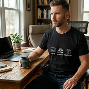 Può includere: Una maglietta nera con testo e grafica bianchi. Il testo recita "NO OFFICE, NO COMMUTE, NO DRESS CODE." La persona è seduta a una scrivania di legno con un laptop e una tazza.