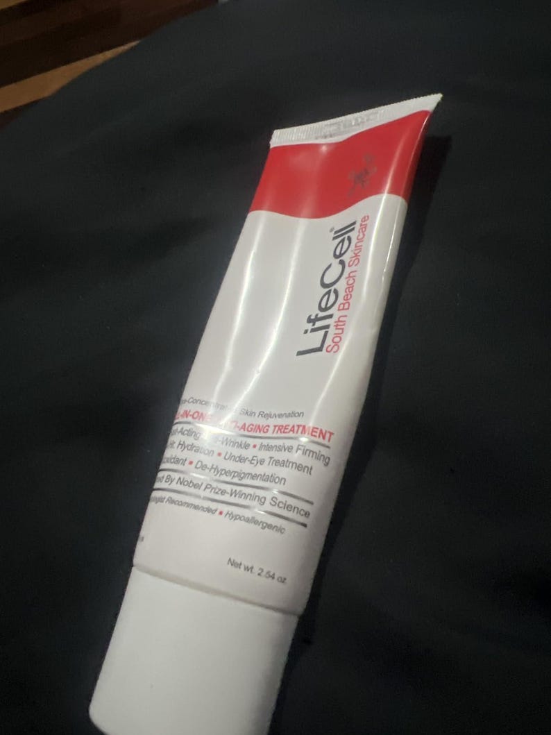 Pu&ograve; includere: Un tubo bianco di LifeCell South Beach Skincare N-ONE Anti-Aging Treatment. Il tubo ha una parte superiore rossa e presenta testo come "Acting", "Wrinkle", "Intensive Firming" e "Net wt. 72 g."