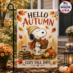 May include: A rectangular garden flag featuring a white background with the text HELLO AUTUMN and COZY FALL DAYS. The design shows a cartoon dog wearing a tan knit hat and plaid scarf, holding a basket of leaves near pumpkins and a stack of books.