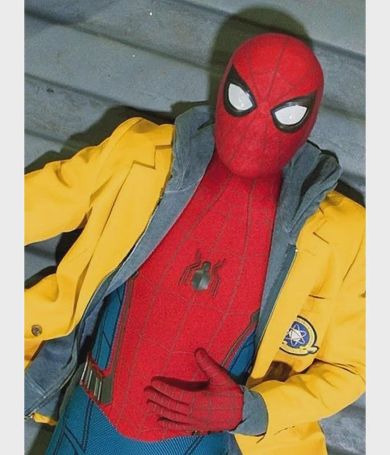 Puede incluir: Un disfraz rojo y azul de Spider-Man con una m&aacute;scara roja y lentes blancos. El disfraz est&aacute; cubierto por una chaqueta amarilla con una sudadera con capucha gris debajo. Un peque&ntilde;o emblema est&aacute; en el pecho del disfraz.