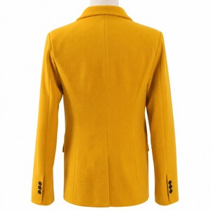 Puede incluir: Un blazer amarillo mostaza con un dise&ntilde;o cl&aacute;sico. La vista trasera muestra un ajuste entallado, solapas con muescas y tres botones en cada manga. El blazer se exhibe en un maniqu&iacute; con cuello de madera.