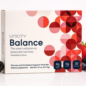 May include: A white box of Unicity Balance, a dietary supplement with a mixed berry flavor. The box features a geometric design in shades of red and pink. Fresh berries, including strawberries, blueberries, and blackberries, are arranged around the box.