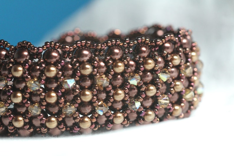 May include: A brown beaded bracelet with gold and clear beads. The bracelet is made with a variety of different sized beads.