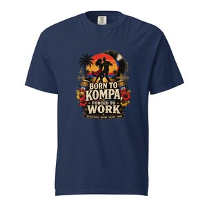 May include: Navy blue t-shirt with a graphic featuring a couple dancing in front of a sunset, a vinyl record, and palm trees. The text reads "Born to Kompa, Forced to Work". The design includes flowers and barrels.