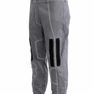 Puede incluir: Pantalones grises con costuras blancas y parches negros en las rodillas. Los pantalones tienen cierre de bot&oacute;n y pu&ntilde;os negros en los tobillos. Los pantalones est&aacute;n hechos de un material duradero.