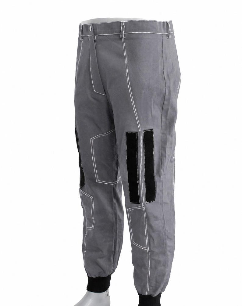 Puede incluir: Pantalones grises con costuras blancas y parches negros en las rodillas. Los pantalones tienen cierre de bot&oacute;n y pu&ntilde;os negros en los tobillos. Los pantalones est&aacute;n hechos de un material duradero.