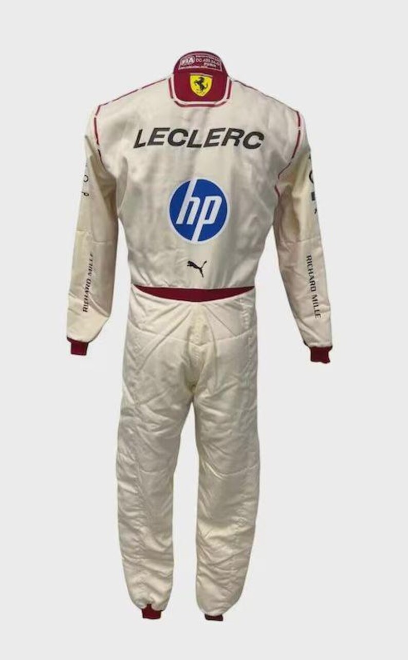 May include: A white racing suit featuring the name LECLERC in black text, a blue HP logo, a black Puma logo, and a Ferrari emblem on the collar. The suit includes red accents on the collar and waist, with Richard Mille text on the sleeves.