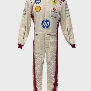 May include: A white and red racing suit featuring various sponsor logos including HP, Shell, UniCredit, and Ceva. The suit displays the number 16, the name Charles, a small flag, and Richard Mille branding on the sleeves with a high collar design.