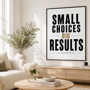 May include: A rectangular wall art print in a black frame featuring the black text SMALL CHOICES and RESULTS with the gold text BIG in the center, followed by the text THE COMPOUND EFFECT, all displayed on a white background with thin horizontal lines.