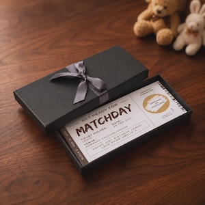 May include: A black rectangular gift box with a grey ribbon bow containing a white ticket for a match between England and Scotland. The ticket includes text details such as the date 24-FEB-2027, venue Wembley Stadium, London, and a gold scratch-off area.