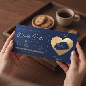 May include: A rectangular navy blue scratch-off card featuring gold foil text that reads Brnch Date and a gold heart with the text Bottomless Brunch. The card includes line art of a croissant, coffee cup, glasses, and cherries with white text.