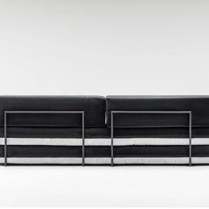 May include: A modern black sofa with a minimalist design. The sofa features a rectangular shape with a dark, textured fabric and a metal frame. The cushions are stacked, with white stripes adding contrast.