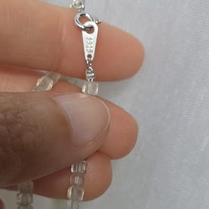以下が含まれることがあります： 淡い緑色の半透明なファセットカットビーズを使用したネックレス。銀色の金属製スプリングリングクラスプが付いており、小さな長方形のタグには「925」の刻印がはっきりと打たれており、スターリングシルバーであることを示しています。
