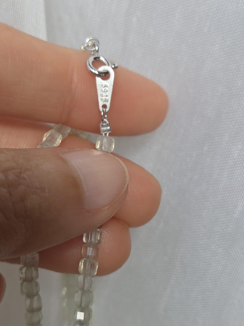 以下が含まれることがあります： 淡い緑色の半透明なファセットカットビーズを使用したネックレス。銀色の金属製スプリングリングクラスプが付いており、小さな長方形のタグには「925」の刻印がはっきりと打たれており、スターリングシルバーであることを示しています。