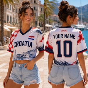 May include: A white V-neck crop top featuring a red and white checkered pattern on the sleeve, the text CROATIA, a small Croatian flag, and a blue coastal city graphic. The back displays the text YOUR NAME and the number 10 in dark blue.